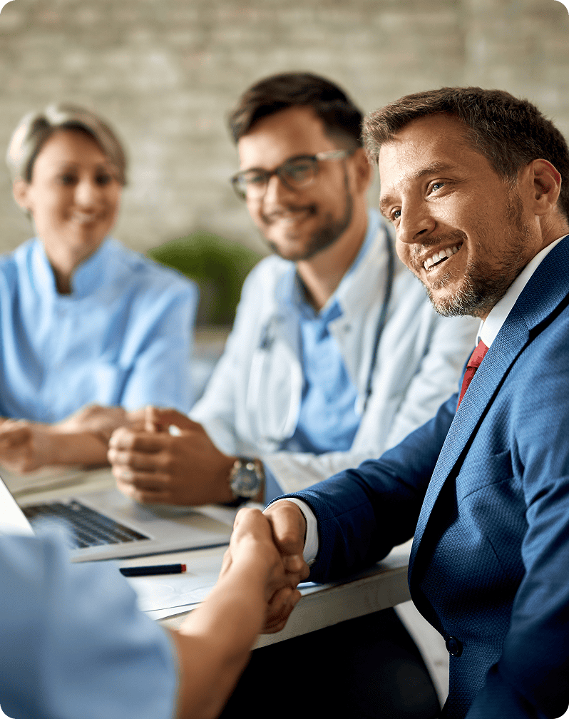 Business professionals shaking hands in a meeting, smiling and engaging.