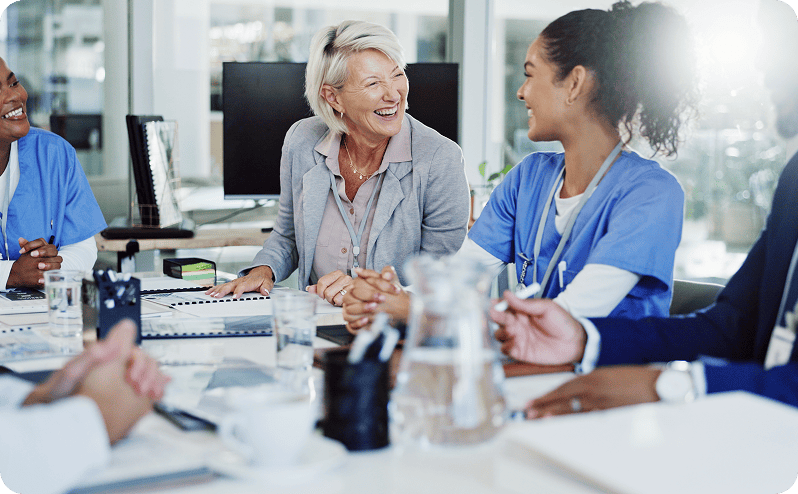 Healthcare professionals and senior woman in a hospital meeting room.