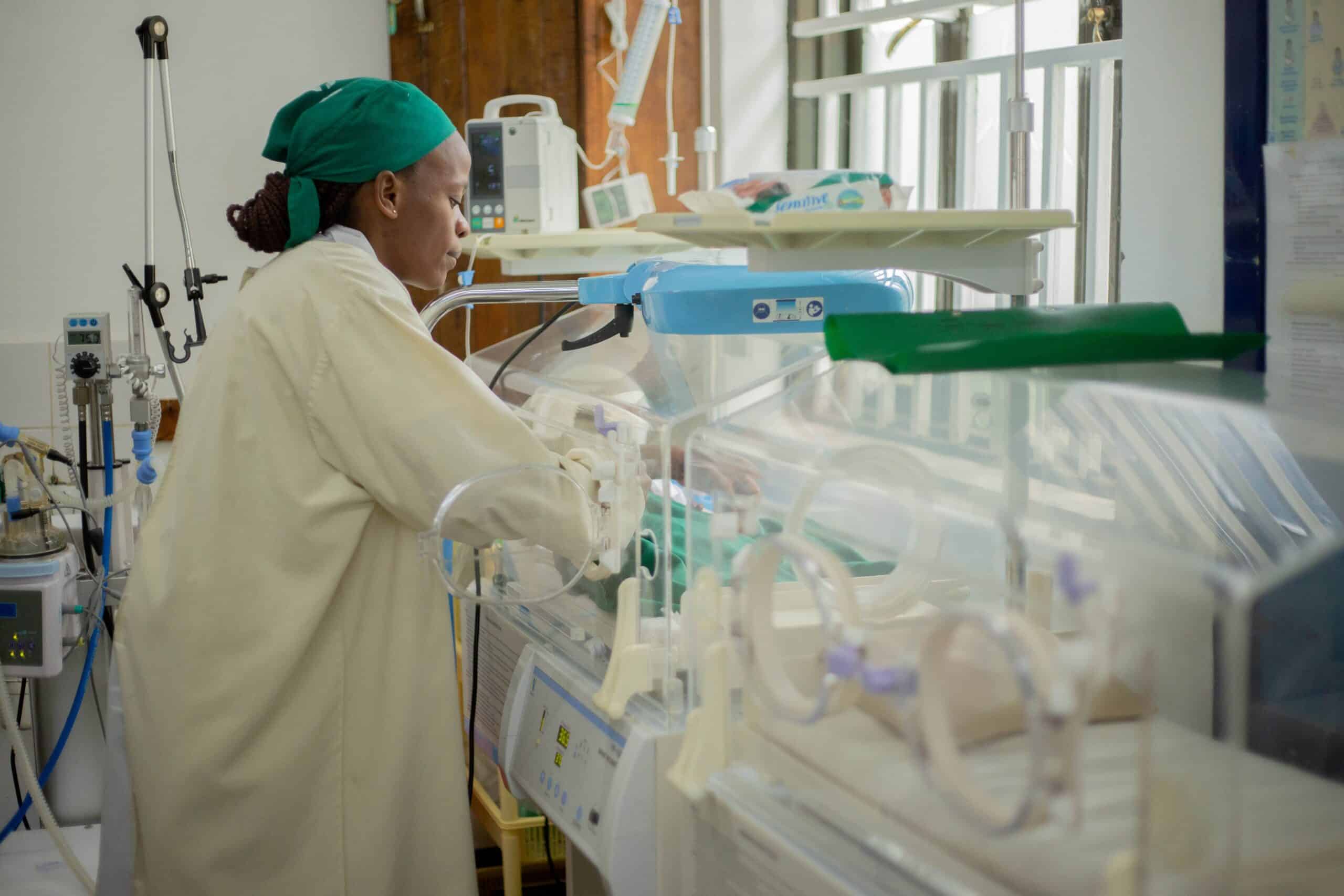Healthcare professional working with neonatal incubator in hospital.