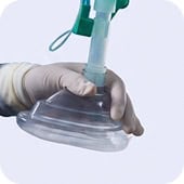 Flexible medical mask being held by a gloved hand, used in healthcare settings.