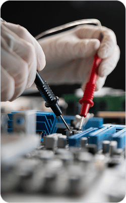 Technician testing medical equipment with multimeter in a healthcare setting.